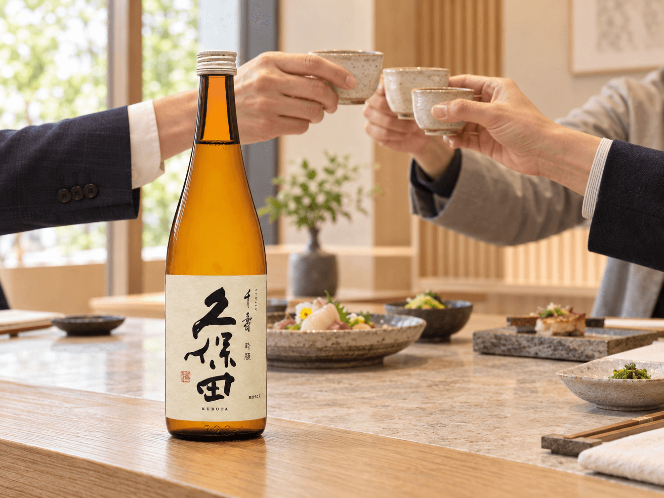 Business partners raising sake cups over a bottle of Kubota at a Japanese dining counter